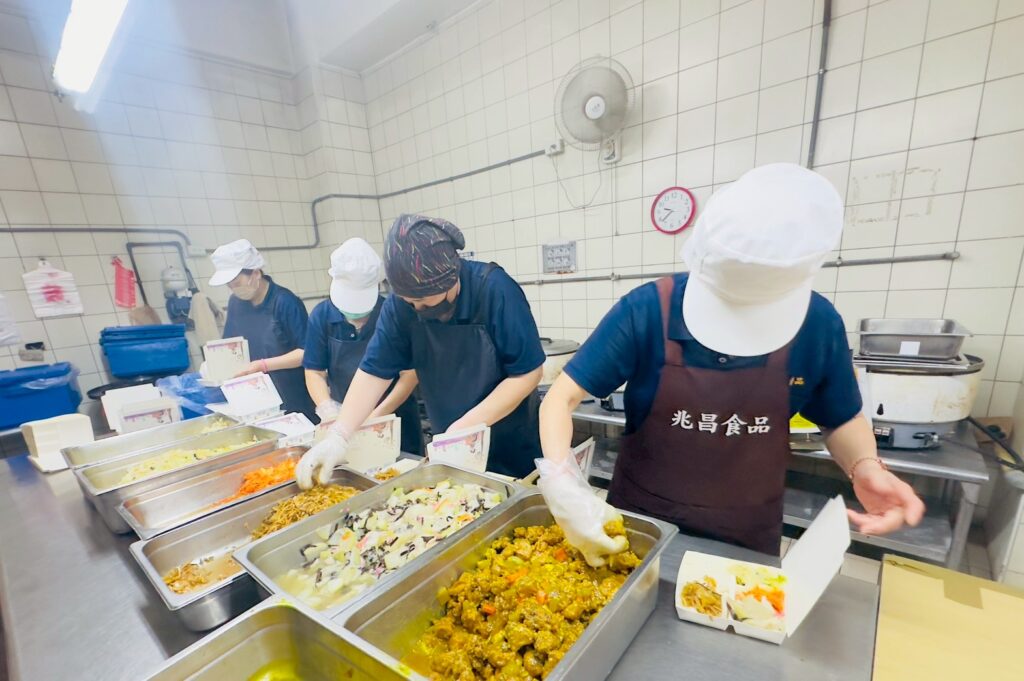 Central kitchen staff preparing lunch boxes in Taoyuan with temperature-controlled meal production process